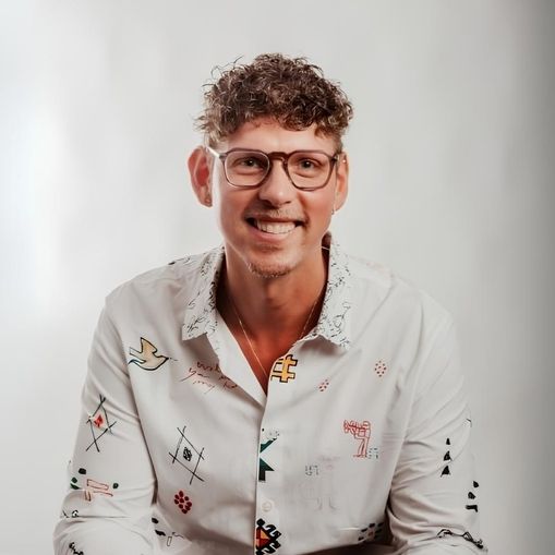 Patrick Pompös sitzt vor einer weißen Wand